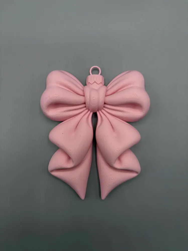 Puffy Ribbon Bow Hanging Ornament — example colour. Includes: One finished item supplied; display accessories are excluded. Approximate dimensions (Width × Depth × Height): 1 supplied: 101.6 × 82.1 × 20.3 mm.