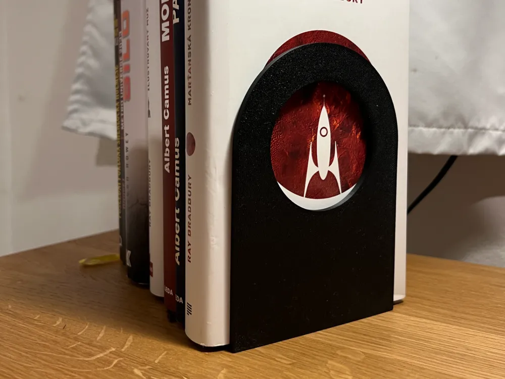 Minimalist Bookend Stand V2 — example colour. Includes: one minimalist bookend stand v2. Approximate dimensions (W × D × H): • Minimalist Bookend Stand V2: 110 × 110 × 155 mm.