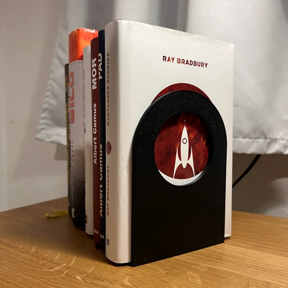 Minimalist Bookend Stand V2 — example colour. Includes: one minimalist bookend stand v2. Approximate dimensions (W × D × H): • Minimalist Bookend Stand V2: 110 × 110 × 155 mm.