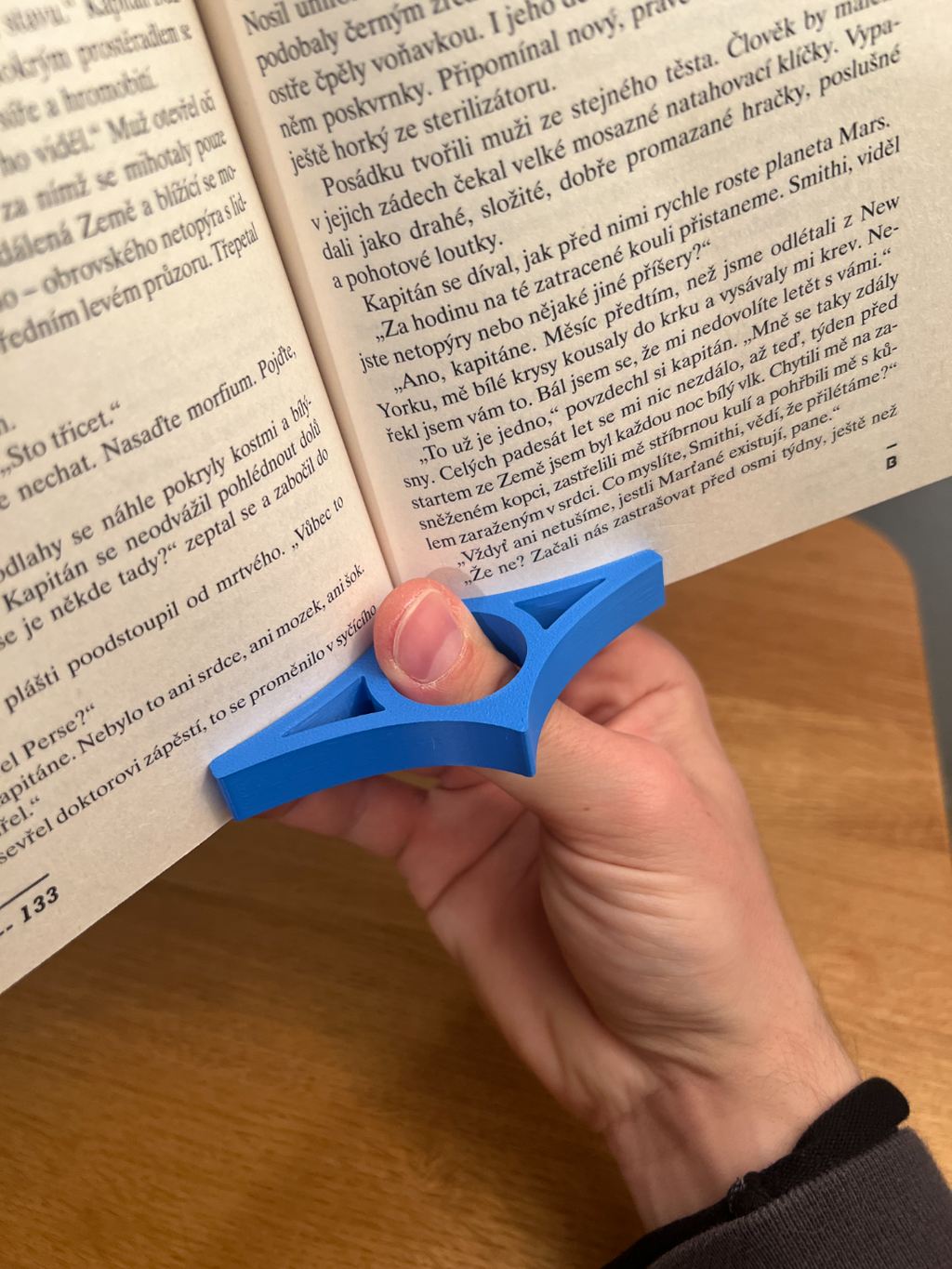 Blue 3D-printed page holder shown in use with a book