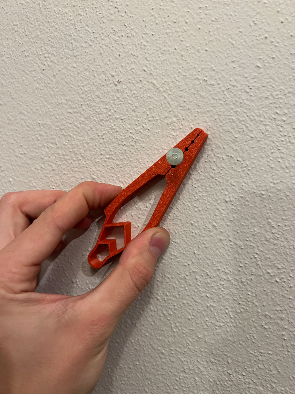 Red 3D-printed nail holder holding an example nail